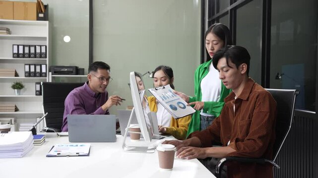 In a boardroom, an Asian team discusses startup financials and business terms. They present strategies on acquisitions, cash flow, and investor relations, innovative approaches for company growth.