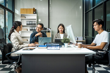 Asian colleagues meet at a desk, discussing business financial terms, investment strategies,...
