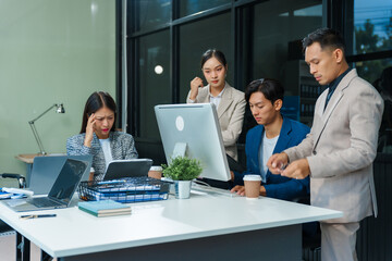 In an office, stressed Asian colleagues discuss financial failures at a desk. business finance, investment strategies, risk management, operational responsibilities to recover stability and success.