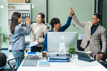 In an office, an Asian team meets at a desk, analyzing financial data on a monitor. They discuss business finance, operational guidelines, and strategies for success, data-driven decision-making.