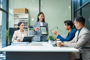 In a boardroom, an Asian team meets at a desk, presenting financial terms and strategies. Executives and employees collaborate, sharing ideas and work guidelines for success during an annual meeting.