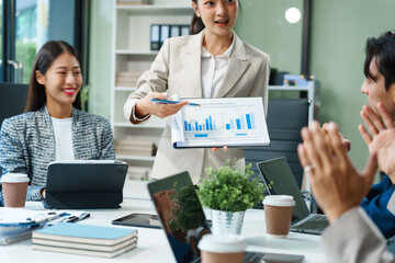 In a boardroom, an Asian team meets at a desk, presenting financial terms and strategies. Executives and employees collaborate, sharing ideas and work guidelines for success during an annual meeting.