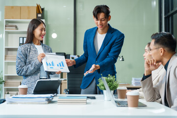 In a boardroom, an Asian team meets at a desk, presenting financial terms and strategies. Executives and employees collaborate, sharing ideas and work guidelines for success during an annual meeting.