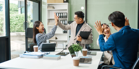 In a boardroom, an Asian team meets at a desk, presenting financial terms and strategies. Executives and employees collaborate, sharing ideas and work guidelines for success during an annual meeting.