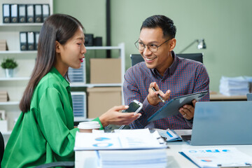 In a boardroom, an Asian team discusses startup financials and business terms. They present strategies on acquisitions, cash flow, and investor relations, innovative approaches for company growth.