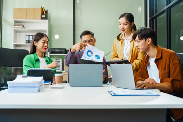 In a boardroom, an Asian team discusses startup financials and business terms. They present strategies on acquisitions, cash flow, and investor relations, innovative approaches for company growth.