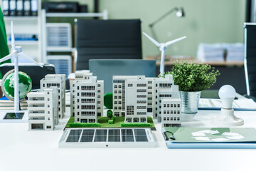 A miniature city model on a desk showcases sustainable technology, with wind turbines and solar panels. renewable energy, eco-friendly architecture, and the future of green urban development.