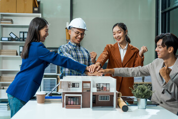 In an office room, architect-engineer team discusses modern house model at desk. They review...