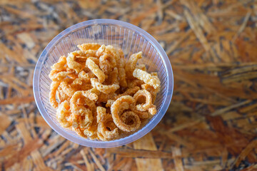 Top view of Pork snack, Pork rind, Pork scratching or crackling in bowl on wooden background, Thai food, Thai stys, Eat with noodles.