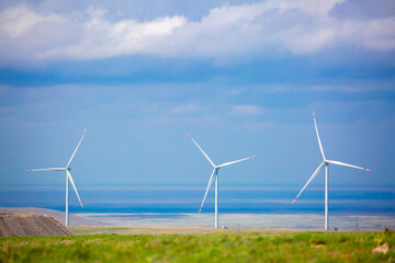 Fleet of power generators in motion. The blades of the wind farm rotate against the sky. The concept of extracting electricity from renewable sources. Wind turbine to generate electricity.