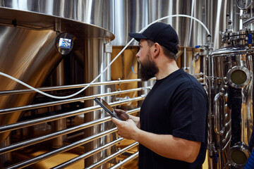 Concentrated man, technologist examining brewing equipment, maintaining thigh standards necessary for quality beer production. Concept of beer, brewery, manufacture, quality control