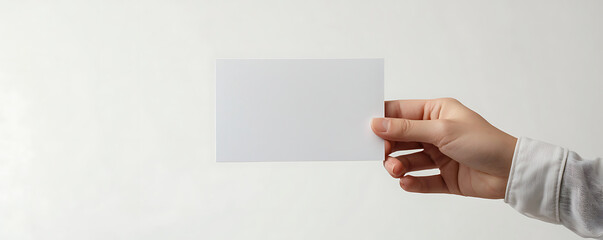 Obraz premium A close-up image of a hand holding a blank white flyer, perfect for design mockups or showcasing brochure designs
