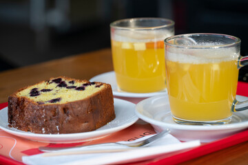 Orange-ginger tea in clear mugs with currant muffin on a table in a cafe. High quality photo