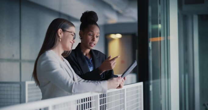 Professional Female Lawyer and Her Assistant Standing in Modern Office Hallway. Two Diverse Young Women Going Through Schedule and Meetings With Clients on Tablet Computer in a Law Firm