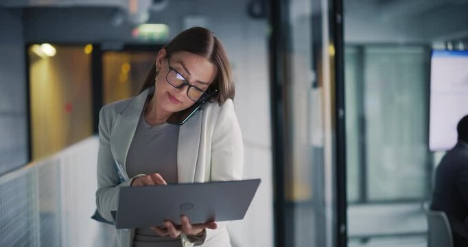 Female Businessman Exiting a Corporate Meeting, Getting on a Phone Call with a Business Partner while Walking. Young Woman Multitasking by Using a Laptop Computer and Smartphone in Office