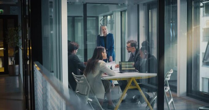 Team of Female and Male Managers Having a Discussion in an Office Meeting Room. Private Equity Businesspeople Analyzing Financial Reports, Planning Future Acquisitions, Brainstorming New Ideas