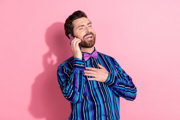 Photo of positive elegant man wear trendy striped clothes hold gadget isolated on pink color background