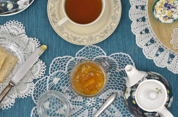 Vintage tea party: scone, jam, cupcake, cup of tea and tea pot. Top view table decorated with retro crocheted napkins.