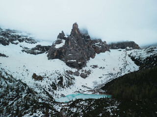 Turquoise water lake with rowing wood boats surrounded by pine trees and snowed mountains reflected...