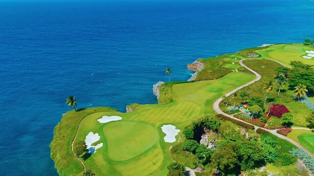 Golf course on the ocean in sunny Florida. Aerial view of green grass and coconut palms on the fairway. Sand bunker and putting green. Green lawns on outdoor sports fields.