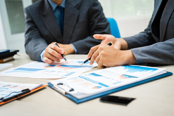 close-up of two professionals' hands meeting at a desk, discussing business strategies over a digital tablet and laptop. teamwork, planning, and communication in a corporate office setting.