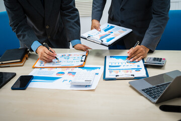 close-up of two professionals' hands meeting at a desk, discussing business strategies over a digital tablet and laptop. teamwork, planning, and communication in a corporate office setting.