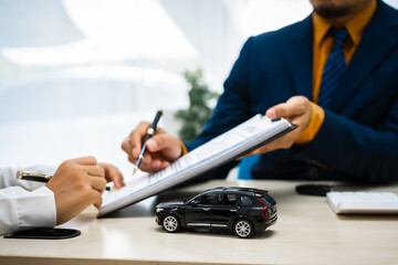 close-up of a car salesman handing the keys to an Asian customer after signing an insurance agreement. business transaction, ownership and customer service in the automotive industry.