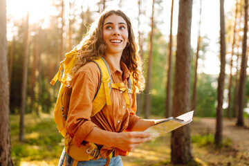 A young woman explores a forest while reading a map in the sunlight, enjoying a beautiful day...