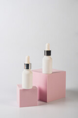 White glass cosmetic bottle in hand, Skin care or sunscreen cosmetic with stylish props on white background.