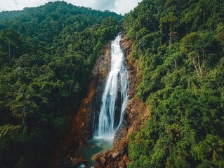 Obraz premium Aerial View of Waterfall Plunging Through Lush Green Forest.