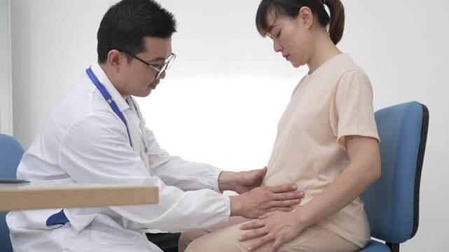 Asian female doctor listens to belly of pregnant mother during a prenatal exam in clinic. doctor provides caring advice, ensuring the health and happiness of the expecting mother and baby.