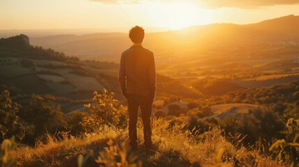 Fototapeta premium Portrait of a man standing on a hilltop, looking out at a valley bathed in the golden light of sunset