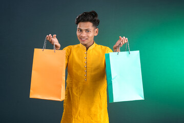 Indian traditional Young handsome man holding and posing with shopping bags on a dark background