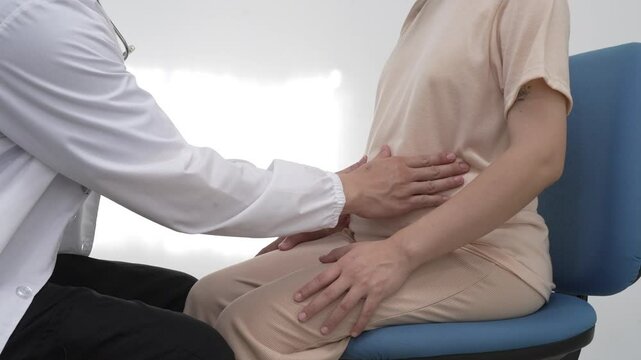 Asian female doctor listens to belly of pregnant mother during a prenatal exam in clinic. doctor provides caring advice, ensuring the health and happiness of the expecting mother and baby.