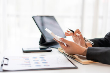 A woman is sitting at a desk with a laptop and a tablet