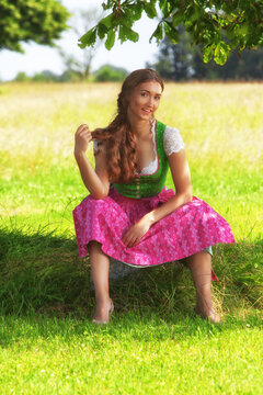 "L&auml;chelnde Frau im Dirndl auf einer Wiese"