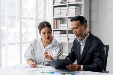 A man and a woman are sitting at a desk looking at a presentation