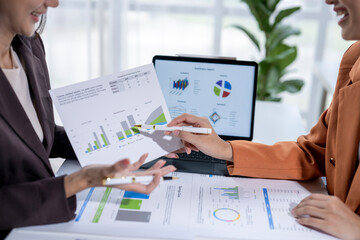 Two businesswomen analyzing financial charts and graphs on a desk