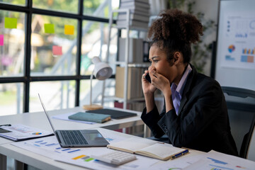 A woman in a business suit is on the phone in a cubicle