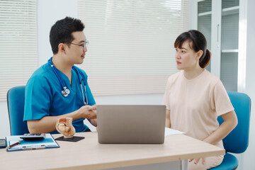 Obraz premium Asian female doctor listens to belly of pregnant mother during a prenatal exam in clinic. doctor provides caring advice, ensuring the health and happiness of the expecting mother and baby.