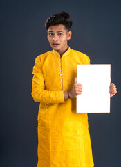 A happy young man is holding and displaying a signboard or placard on a dark background.