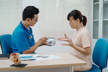 Obraz premium Asian female doctor listens to belly of pregnant mother during a prenatal exam in clinic. doctor provides caring advice, ensuring the health and happiness of the expecting mother and baby.