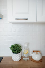 Fresh herbs and a kettle on a wooden kitchen counter with modern decor and bright lighting
