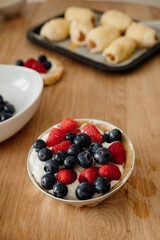 Delicious dessert bowl with fresh berries served on a wooden tabletop in a cozy kitchen setting