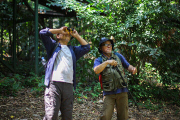 Two Asian Elderly Man Looking At The View Using Binoculars While Hiking And Trekking