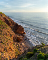Scenic view of rolling grass hills meeting the ocean, with a charming boardwalk winding through the landscape, capturing the serene beauty of coastal nature.