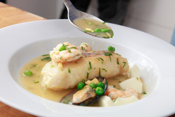Merluza en salsa verde con guisantes y gambas. Comida de chef. Hake in green sauce with peas and shrimp. Chef's meal.