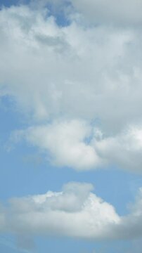 Blue sky with white fluffy clouds, vertical timelapse video of cloudscape passing by on a cloudy day, natural weather background
