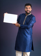 A happy young man is holding and displaying a signboard or placard on a dark background.