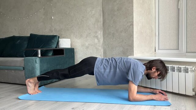 Sportsman performing the plank exercise in a cozy living room, showcasing strength and fitness in a domestic setting